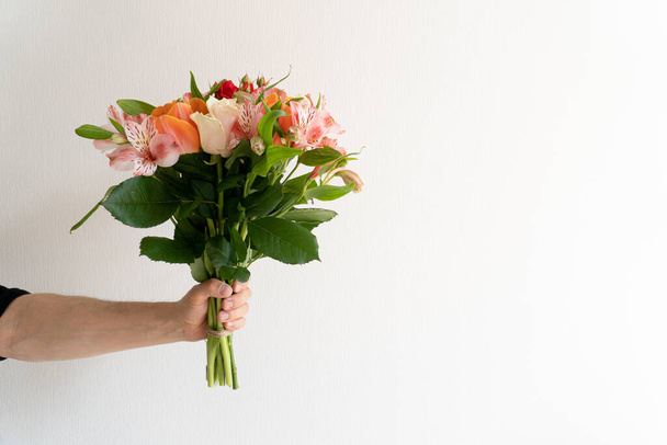 Bouquet of beautiful flowers in mans hand on white background. - Zdjęcie, obraz