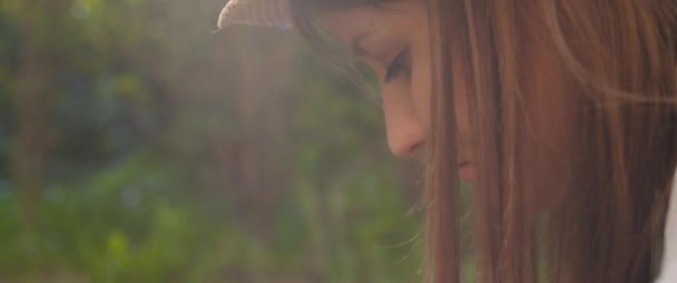 Close up de uma bela jovem com chapéu e cabelos castanhos longos olhando para baixo enquanto trabalhava no jardim ao pôr do sol. LOW MOTION, SHALLOW DOF, BMPCC 4K
.   - Filmagem, Vídeo