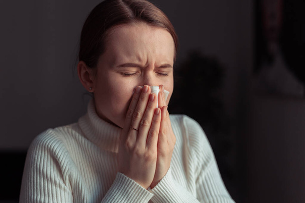 Cough in tissue covering nose and mouth when coughing. European woman sick with flu at home. - Photo, image