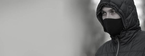 Retrato de cerca de un joven europeo con una máscara protectora negra para protegerse contra la infección por el virus de la gripe o coronavirus.Banner.Espacio para copiar el texto.Fotografía en blanco y negro
 - Foto, Imagen