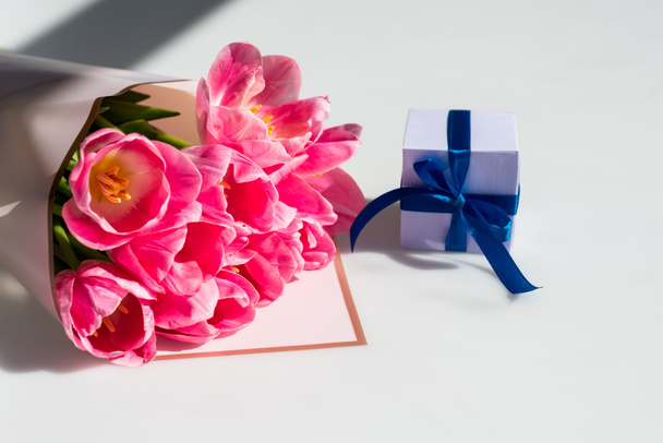 bouquet of pink tulips near small gift box on white, mothers day concept  - Zdjęcie, obraz