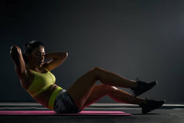 Sportswoman doing crunches in gym. - Фото, зображення