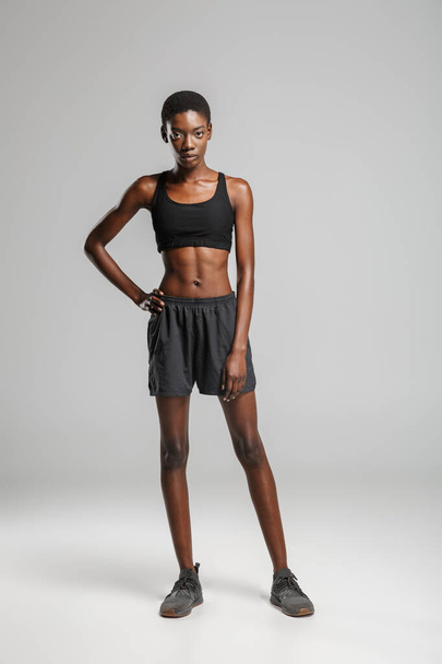 Image of athletic african american woman in sportswear posing and looking at camera isolated over white background - Zdjęcie, obraz