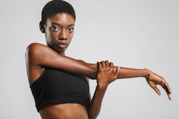 Image of athletic african american woman stretching her arms while working out isolated over white background - Photo, image