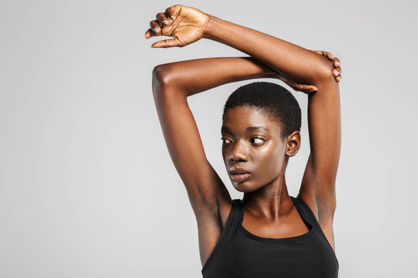 Image of athletic african american woman stretching her arms while working out isolated over white background - Foto, immagini