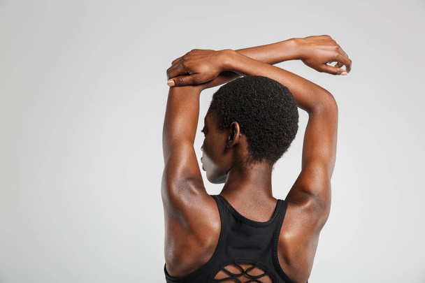 Image from back african american woman stretching her arms while working out isolated over white background - Foto, Bild