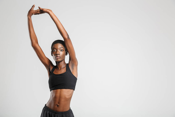Image of athletic african american woman stretching her arms while working out isolated over white background - Фото, зображення