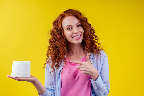 redhaired curls ginger female pointing finger at eco hygiene paper on studio yellow background - Fotografie, Obrázek