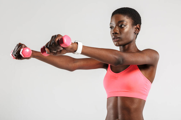 Image of african american sportswoman doing exercise with dumbbells isolated over white background - Foto, immagini