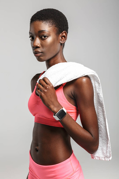 Image of african american sportswoman with towel drinking water while working out isolated over white background - Fotó, kép