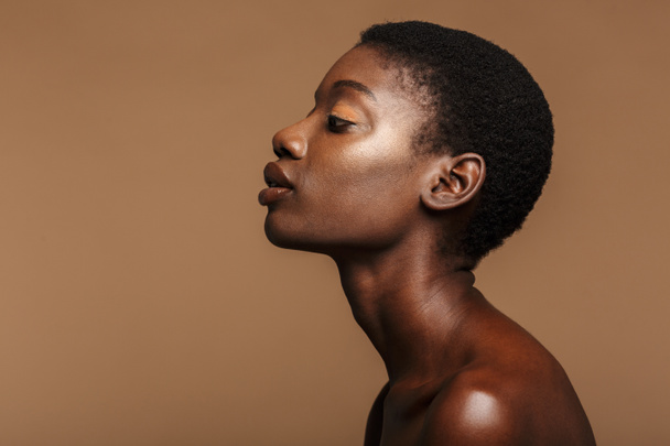Beauty portrait of attractive young half-naked african woman with short black hair isolated over beige background - Foto, afbeelding