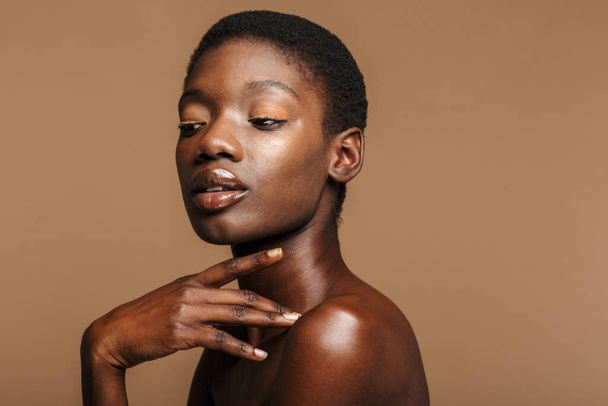 Beauty portrait of attractive young half-naked african woman with short black hair isolated over beige background - Φωτογραφία, εικόνα