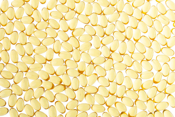 Softgels of Omega-3 on isolated background. Texture of yellow capsules on isolated white background. Medical medicament of polyunsaturated fatty acids. Fish oil capsules, close up. - Foto, Imagen