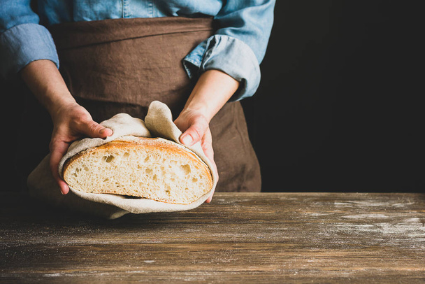 A woman in an apron holds various fresh bread loaves with golden crisp in her hands. Homemade alternative bread - Foto, immagini
