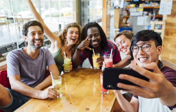 Un grupo de amigos multiétnicos tomando una selfie en un restaurante. Concepto de amistad
 - Foto, imagen