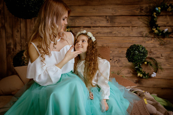 Bela e inteligentemente vestida mãe com sua filha no estúdio com decoração de primavera
 - Foto, Imagem