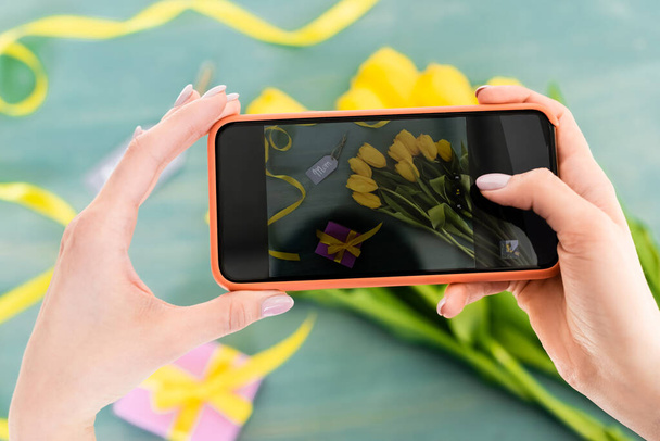 enfoque selectivo de la mujer que toma la foto de los tulipanes amarillos, presente y mamá etiqueta de letras en la superficie texturizada, madre concepto de día
  - Foto, Imagen