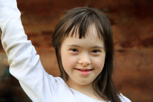 Portret van een klein meisje glimlachend op een bruine achtergrond - Foto, afbeelding