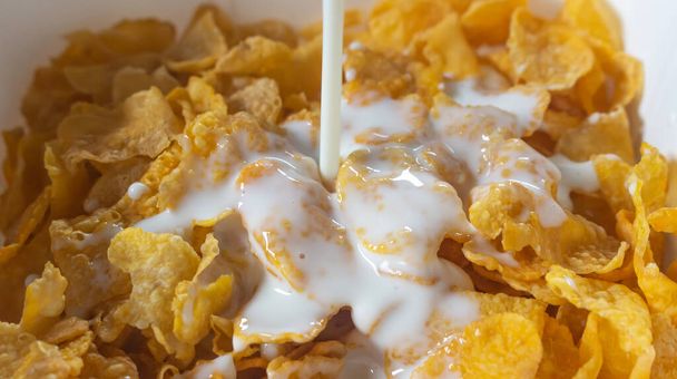 Cereal de desayuno. Copos dorados tostados de maíz con leche
 - Foto, imagen