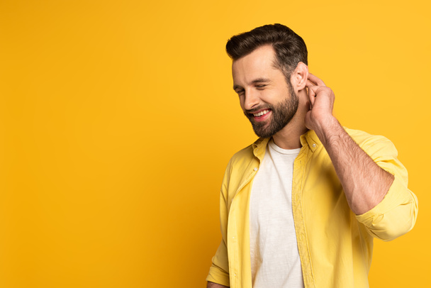 Smiling man with closed eyes showing gesture from deaf and dumb language on yellow background - Fotografie, Obrázek