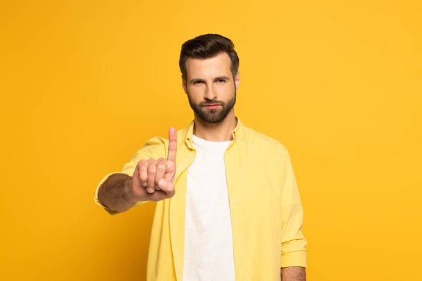 Handsome man pointing with finger on yellow background - Фото, зображення