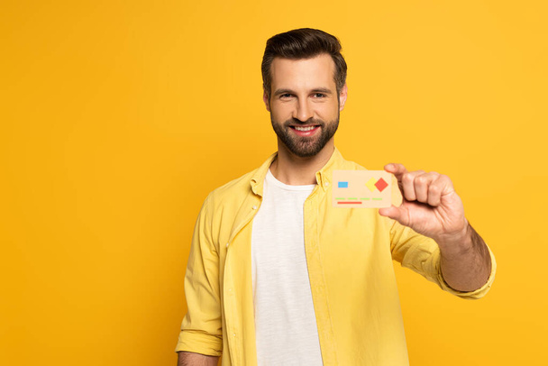 Szelektív fókusz mosolygó ember gazdaság modell hitelkártya izolált sárga  - Fotó, kép