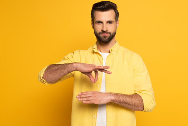 Man showing gesture in deaf and dumb language on yellow background - Фото, изображение