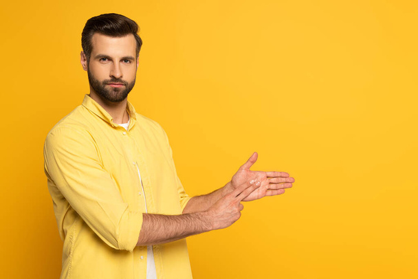 Sarı arkaplanda işaret dili kullanırken el kol hareketi yapan yakışıklı adam - Fotoğraf, Görsel