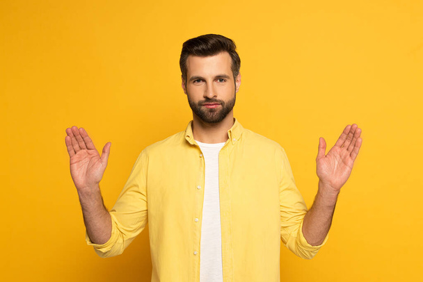 Handsome man looking at camera and pointing with hands on yellow background - Фото, зображення