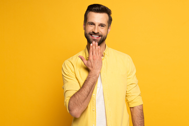 Smiling man looking at camera while showing word speak in sign language on yellow background - Foto, immagini