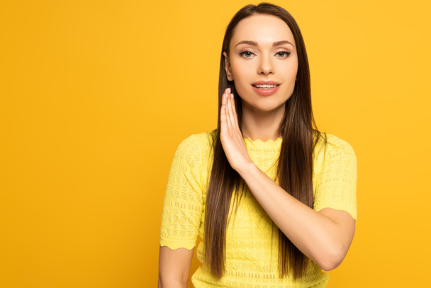 Attractive woman smiling and using deaf and dumb language isolated on yellow  - Fotografie, Obrázek
