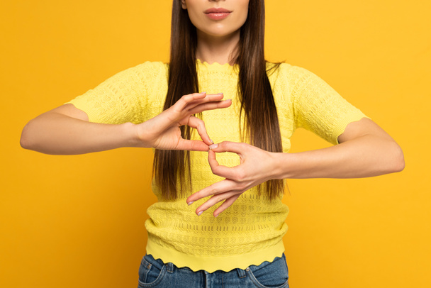 Vista recortada de la mujer mostrando el signo de interpretación en lenguaje sordo y mudo sobre fondo amarillo
 - Foto, imagen