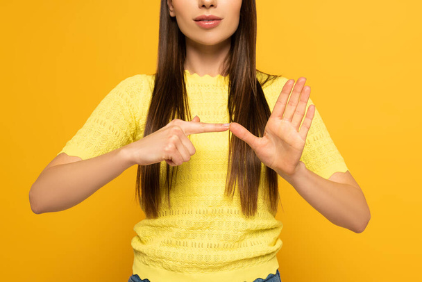 Обрезанный вид женщины, показывающей жест языка жестов на желтом фоне
 - Фото, изображение
