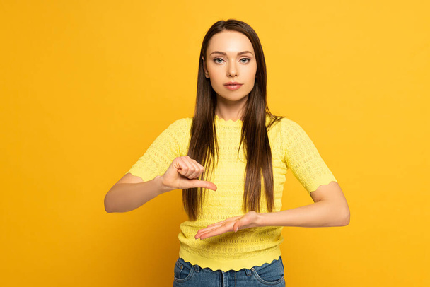 Hermosa mujer haciendo gestos mientras usa lenguaje de señas sobre fondo amarillo
 - Foto, imagen