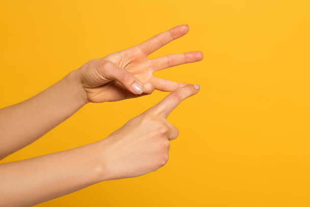 Cropped view of woman gesturing while using sign language isolated on yellow  - Foto, imagen