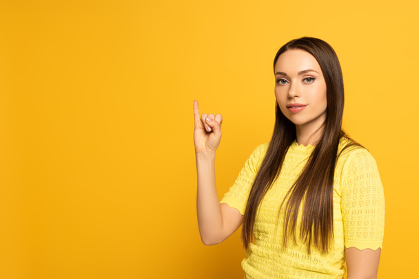 Beautiful woman showing letter from sign language on yellow background - Fotó, kép