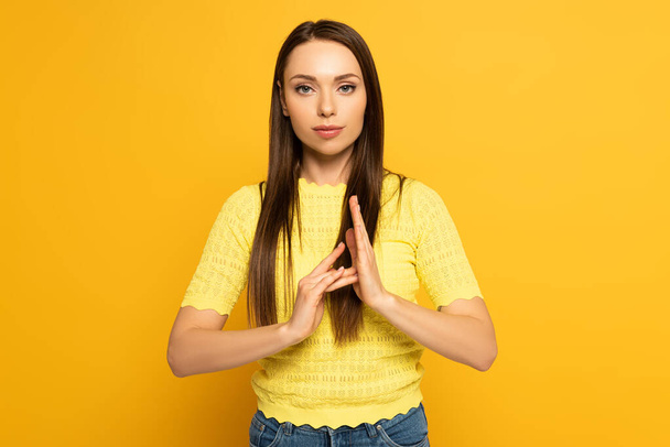 Молодая женщина показывает жест во время использования глухих и немых язык на желтом фоне
 - Фото, изображение