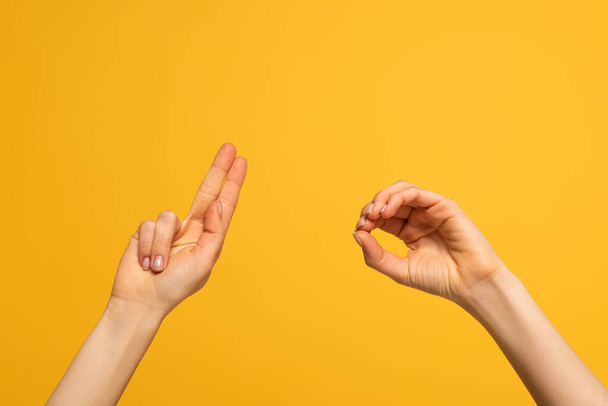 Cropped view of woman showing letters from deaf and dumb language on yellow background - Photo, Image