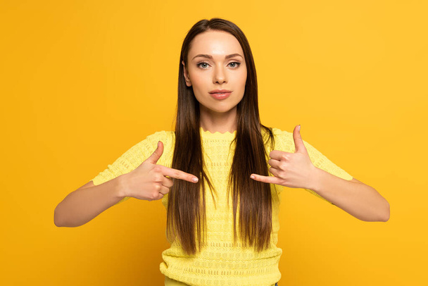 Çekici kız işaret dilini sarı arka planda kullanırken el kol hareketi yapıyor - Fotoğraf, Görsel