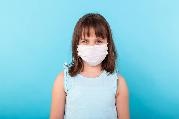 Little girl, a child in a medical mask on a blue background. The concept of an epidemic, protection from disease, coronavirus, covid-19. - 写真・画像