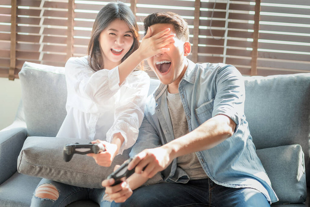Ασιάτες εραστές ζευγάρι απολαμβάνουν και να παίξουν το παιχνίδι κονσόλα στις διακοπές κάνουν πιο ποιοτικό χρόνο της ευτυχίας μαζί στο σπίτι - Φωτογραφία, εικόνα