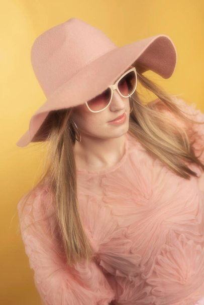 Retro 1960s summerly fashion woman in pink sweater, hat and sunglasses. - Фото, изображение