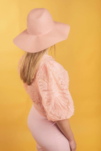 Retro 1960-tych lato moda kobieta w różowym swetrze, spodnie i kapelusz. Widok z tyłu. - Zdjęcie, obraz