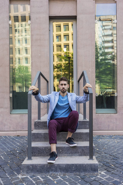 Portrait of happy bearded young man sitting on steps - Foto, Imagem
