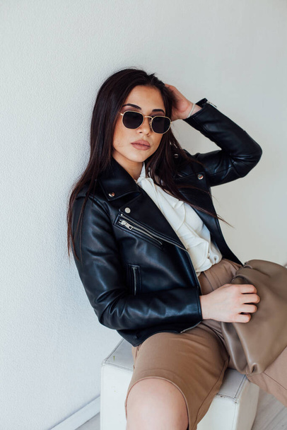 Portrait of a beautiful fashionable brunette woman in a black jacket and glasses - Foto, Imagen