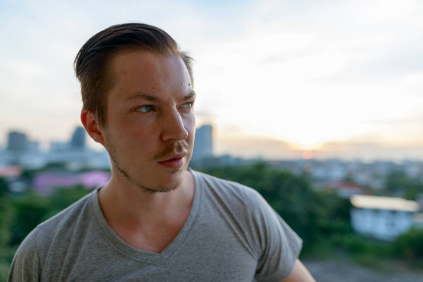 Portrait of young handsome man with stubble beard against view of the city outdoors - Foto, Bild