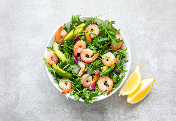 Shrimp arugula salad with avocado slices, high angle view of ready-to-eat keto-friendly dish, simple and healthy recipe - Фото, изображение