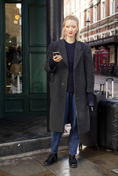 London, UK - 15 January 2020 Fashionable people on the street . Street style. Blonde woman in a black wool coat posing in the bright sun - Zdjęcie, obraz