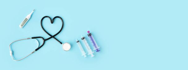 Stethoscoop vormt een hart en andere medische instrumenten op pastelblauwe achtergrond met kopieerruimte voor tekst. Begrip "geneeskunde en gezondheid". - Foto, afbeelding