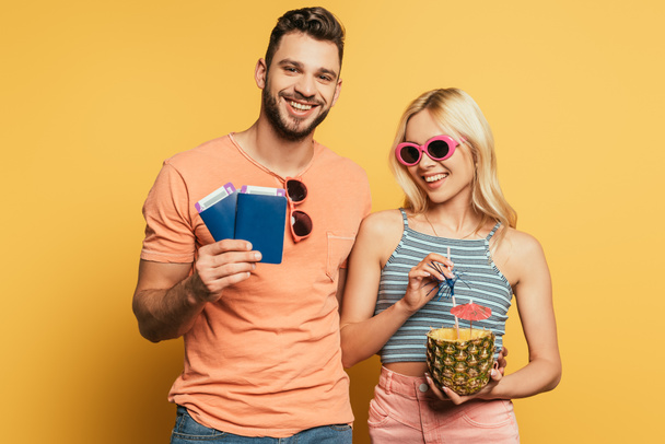 happy man holding documents near smiling girl with cocktail in pineapple on yellow background - Photo, image